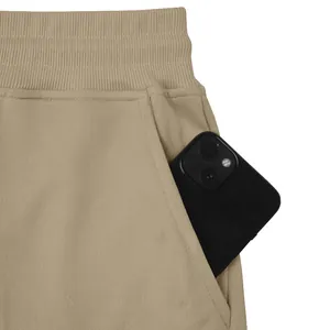 Detail view of khaki heavy weight sweatpants showing a deep side pocket with a phone