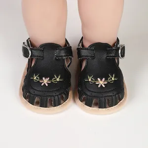 Detalle de sandalias de verano negras para bebé con bordados florales y suelas blandas.