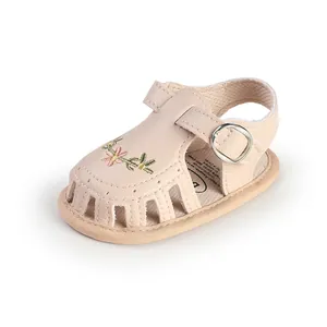 Dettaglio sandali rosa per neonata con ricami floreali e design traforato traspirante.