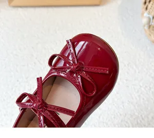 Close-up of glossy red patent leather girls' shoes featuring an elegant double bow detail