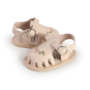 Primo piano di sandali beige per neonata con ricami floreali e fibbia in metallo