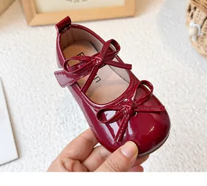 Macro view of burgundy patent leather Mary Jane shoe with double bows for girls