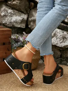 Detailopname van zwarte platform sandalen met gesp en kurkzool buiten gedragen.