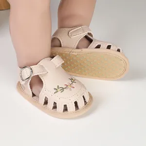 Dettaglio di sandali beige per neonata con ricami floreali e suola antiscivolo di sicurezza