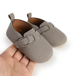 Detailed view of grey suede baby shoes with a buckle strap and retro flat design