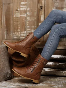 Detailaufnahme brauner, mittelhoher Martin-Stiefel mit Reißverschluss und Gürtelschnalle.