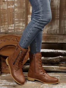 Nahaufnahme brauner Damenstiefel mit Reißverschluss und Schnalle, kombiniert mit Jeans.