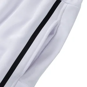 Detalle macro que muestra el bolsillo y la franja lateral negra en pantalones blancos de chándal