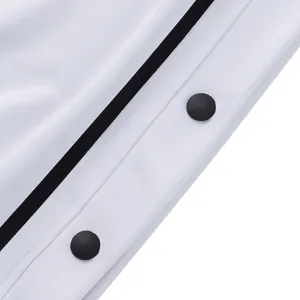 Detalle de pantalones deportivos gruesos con botones de presión negros y franja lateral.