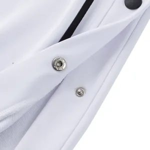 Vista detallada de los botones de presión laterales en pantalones deportivos blancos.