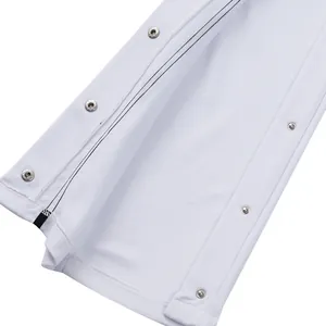 Primer plano de los botones de presión metálicos en la costura lateral del pantalón blanco.