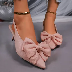 Close-up of pink pointed toe slingback high heels with large bow detail and thin heel.