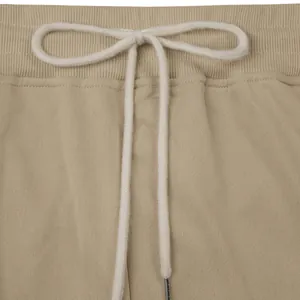Close-up of beige heavy cotton men's sweatpants with white drawstring waist detail