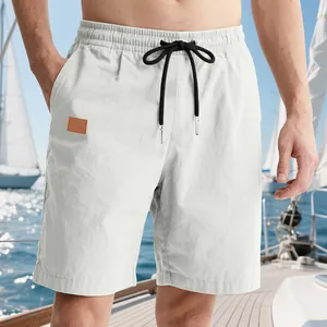 Detailed view of men's white casual shorts with black drawstring and patch on a boat