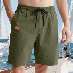 Detail view of olive green men's beach shorts with black drawstring on a yacht deck