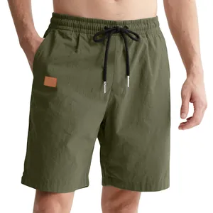 Close-up of men's olive green casual shorts with drawstring waist and leather patch.