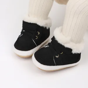 Vista detallada de zapatillas de invierno negras para bebé con forro de piel sintética blanca