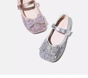 Close-up detail of glitter children's Mary Jane shoes with sparkling bow accents.