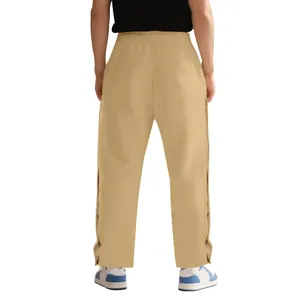 Vista detallada del pantalón de chándal caqui con botones laterales y ajuste relajado.