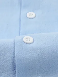 Close-up of fabric texture and white buttons on a blue men's cotton linen shirt