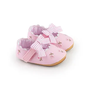 Dettaglio di scarpe da principessa rosa per neonata con ricami floreali e fiocco a righe.