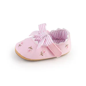 Primo piano di scarpa rosa per neonata con ricami floreali e fiocco a righe