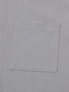 Macro view showing the textured fabric and stitched pocket of a gray linen-cotton shirt