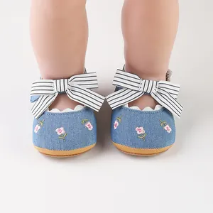 Dettaglio ravvicinato di scarpe neonata in denim blu con fiocchi a righe e ricami floreali