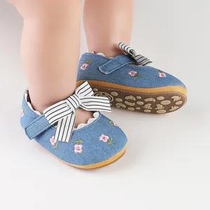 Dettaglio del motivo a fiori ricamati e fiocco a righe su scarpe in denim per neonata