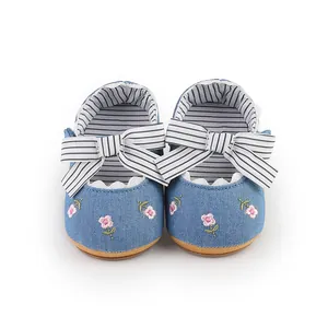 Vista dettagliata delle scarpe da principessa per neonata con fiori ricamati e fiocco.