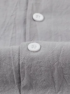 Close-up detail of grey linen-cotton shirt showing white buttons and fabric texture