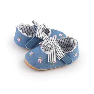 Primo piano di scarpine in denim per neonata con ricami floreali e fiocco a righe