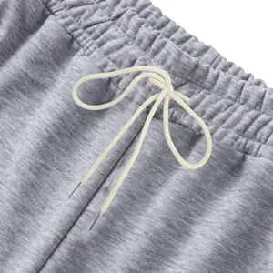 Primer plano de la cintura elástica y los cordones crema en pantalones de chándal grises