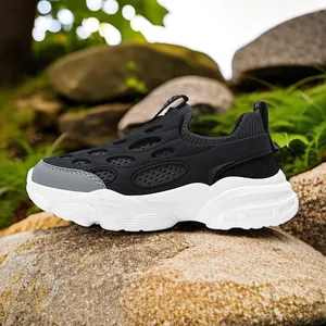 Zapatillas de malla transpirable para niños en blanco y negro, vista sobre roca natural