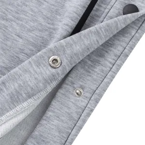 Detalle de botones a presión de metal plateado en pantalones de chándal grises pesados