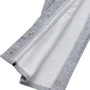 Detalle de pantalones deportivos grises con botones de presión laterales y textura