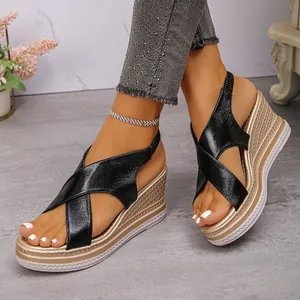 Nahaufnahme von stilvollen schwarzen Keilsandalen für Damen mit goldener Keilsohle