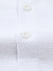 Macro detail of white cotton linen shirt showing textured fabric and buttons