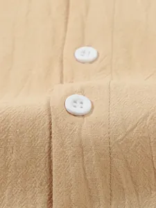 Close-up showing the textured cotton linen fabric and white buttons of a men's beige shirt