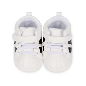 Top view of white baby sneakers with black stripes and shell toe design for toddlers.
