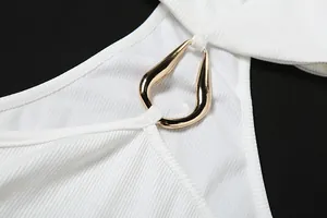 Dettaglio ravvicinato di top halter bianco a coste con elegante anello in metallo dorato a goccia
