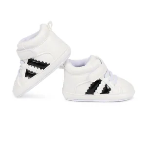 Detail view of white infant high-top sneakers with black stripes and Velcro strap