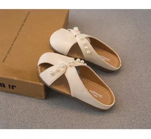 Vista detallada de las pantuflas beige para niñas con elegantes decoraciones de perlas.