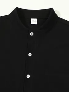 Detail view of men's black stand-collar shirt featuring white buttons and fabric label