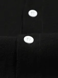Macro detail of breathable black cotton linen shirt fabric with white button accent