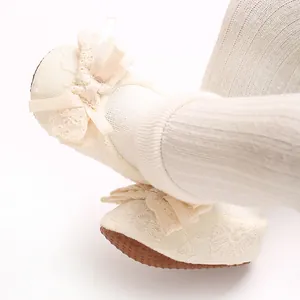 Close-up detail of cream lace trim and ribbon bow on infant anti-slip cotton socks shoes