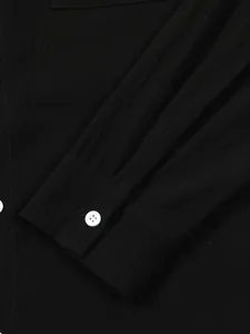 Detailed close-up view of a black cotton linen shirt cuff featuring a white button