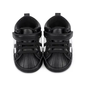 Top-down view of black baby sneakers with iconic shell toe and white stripes detail.