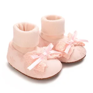 Close-up detail of soft pink baby girl sock shoes featuring a delicate lace bow design
