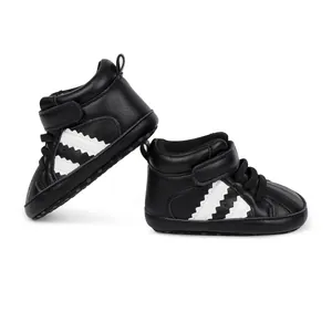 Macro detail of black baby high-top sneakers with distinctive white zig-zag side stripes.